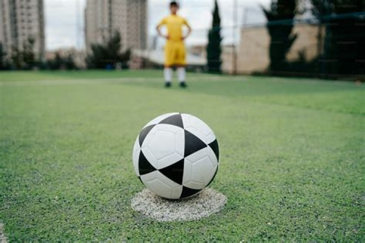 a soccer ball sitting on top of a lush green field under a cloudy sky