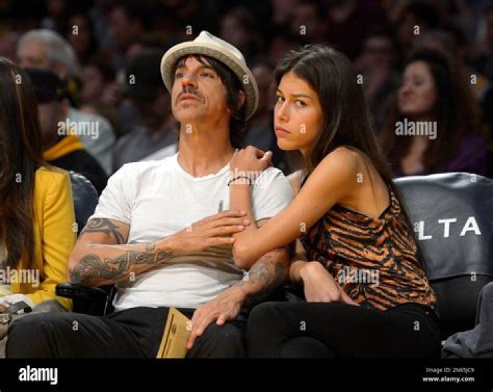 Anthony Kiedis, left, of the Red Hot Chili Peppers of sits with model